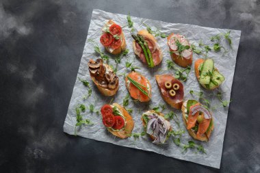 Brushetta veya geleneksel Ispanyol tapas. Italyan Antipasti aperatifler ile meze. Prosciutto ile küçük sandviç çeşitleri, kiraz domates, somon, krem peyniri, salatalık, turp, kuşkonmadan