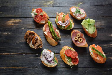 Brushetta veya geleneksel Ispanyol tapas. Italyan Antipasti aperatifler ile meze. Prosciutto ile küçük sandviç çeşitleri, kiraz domates, somon, krem peyniri, salatalık, turp, kuşkonmadan