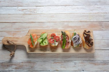 Brushetta veya geleneksel Ispanyol tapas. Italyan Antipasti aperatifler ile meze. Prosciutto ile küçük sandviç çeşitleri, kiraz domates, somon, krem peyniri, salatalık, turp, kuşkonmadan