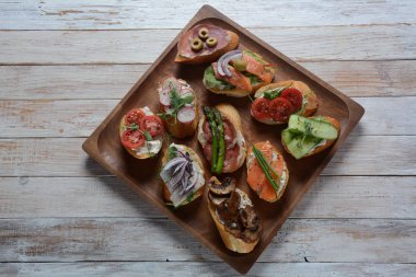 Brushetta veya geleneksel Ispanyol tapas. Italyan Antipasti aperatifler ile meze. Prosciutto ile küçük sandviç çeşitleri, kiraz domates, somon, krem peyniri, salatalık, turp, kuşkonmadan
