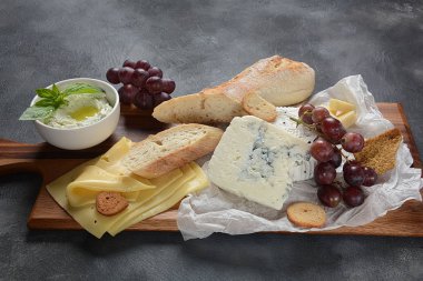 Peynir tabağı, çeşitli peynir, üzüm, koyu arka planda aperatifler. İtalyan, Fransız peynir Starter