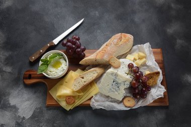 Peynir tabağı, çeşitli peynir, üzüm, koyu arka planda aperatifler. İtalyan, Fransız peynir Starter