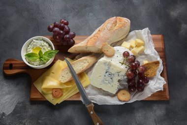 Peynir tabağı, çeşitli peynir, üzüm, koyu arka planda aperatifler. İtalyan, Fransız peynir Starter