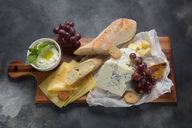 Peynir tabağı, çeşitli peynir, üzüm, koyu arka planda aperatifler. İtalyan, Fransız peynir Starter
