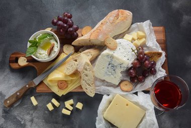 Peynir tabağı, çeşitli peynir, üzüm, koyu arka planda aperatifler. İtalyan, Fransız peynir Starter