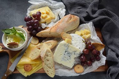 Peynir tabağı, çeşitli peynir, üzüm, koyu arka planda aperatifler. İtalyan, Fransız peynir Starter