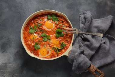 Shakshuka , orta doğu geleneksel ev yapımı kahvaltı- kızarmış yumurta, soğan, biber, domates ve maydanoz koyu bir arka plan üzerinde bir tavada 