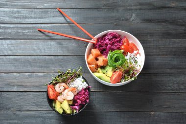 Organik gıda. Taze deniz ürünleri yemek tarifi. İki taze somon, karides, pirinç, kırmızı lahana, avokado, domates ile kase poke ve ahşap arka plan üzerinde turp lahanası. Gıda kavramı Poke kase 