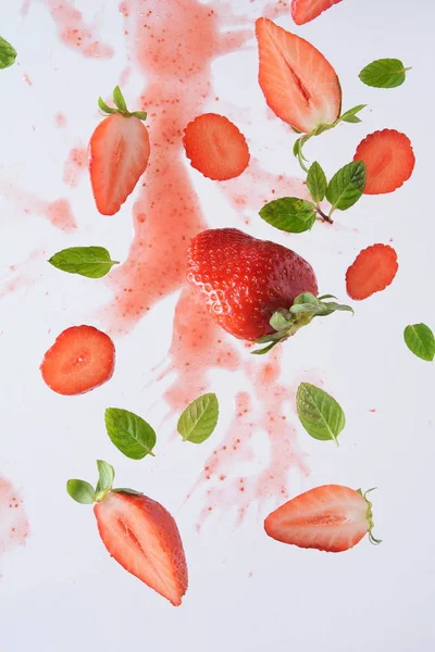 Flying fresh strawberries with mint leaves. Food levitation concept. Creative food layout.