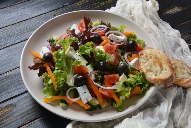 Taze salatalık, kiraz domates, tatlı biber, marul, kırmızı soğan, zeytin ve zeytinyağı ile Yunan salatası koyu ahşap rustik arka plan . Sağlıklı gıda kavramı