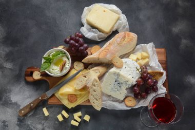 Çeşitli peynirler, üzümler, koyu arka planda atıştırmalıklar içeren peynir tabağı. İtalyan, Fransız peyniri başlangıç 