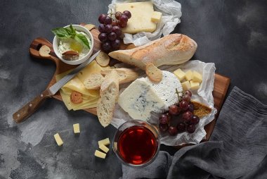 Çeşitli peynirler, üzümler, koyu arka planda atıştırmalıklar içeren peynir tabağı. İtalyan, Fransız peyniri başlangıç 