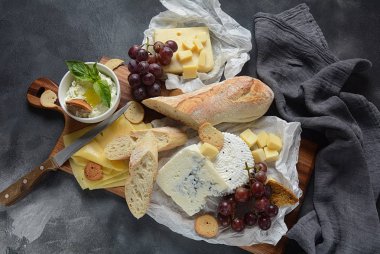 Çeşitli peynirler, üzümler, koyu arka planda atıştırmalıklar içeren peynir tabağı. İtalyan, Fransız peyniri başlangıç 