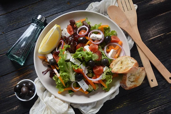 Taze salatalık, kiraz domates, tatlı biber, marul, kırmızı soğan, zeytin ve zeytinyağı ile Yunan salatası koyu ahşap rustik arka plan . Sağlıklı gıda kavramı