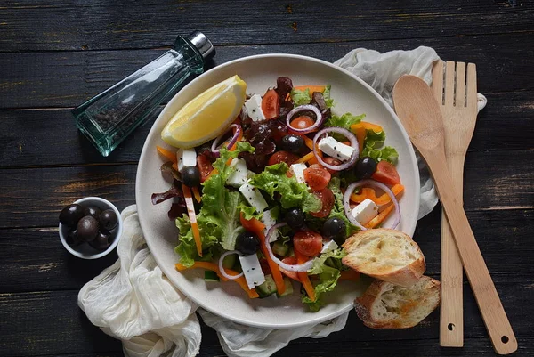 Taze salatalık, kiraz domates, tatlı biber, marul, kırmızı soğan, zeytin ve zeytinyağı ile Yunan salatası koyu ahşap rustik arka plan . Sağlıklı gıda kavramı