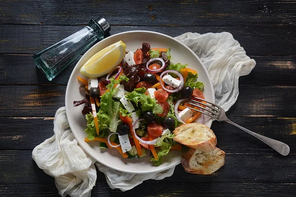 Taze salatalık, kiraz domates, tatlı biber, marul, kırmızı soğan, zeytin ve zeytinyağı ile Yunan salatası koyu ahşap rustik arka plan . Sağlıklı gıda kavramı
