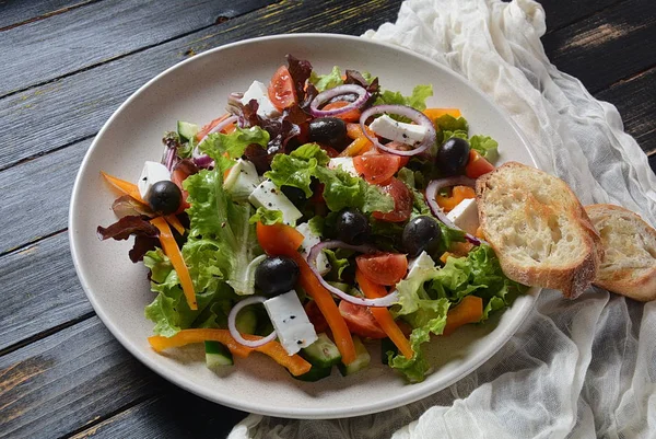 Taze salatalık, kiraz domates, tatlı biber, marul, kırmızı soğan, zeytin ve zeytinyağı ile Yunan salatası koyu ahşap rustik arka plan . Sağlıklı gıda kavramı