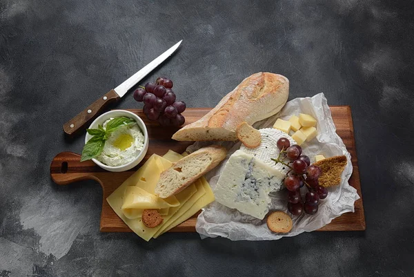 Çeşitli peynirler, üzümler, koyu arka planda atıştırmalıklar içeren peynir tabağı. İtalyan, Fransız peyniri başlangıç 