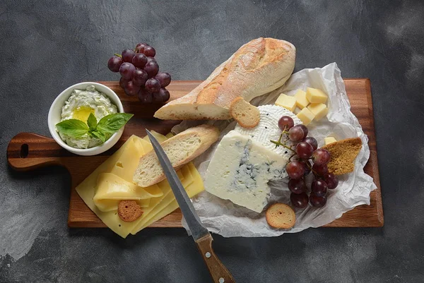 Çeşitli peynirler, üzümler, koyu arka planda atıştırmalıklar içeren peynir tabağı. İtalyan, Fransız peyniri başlangıç 
