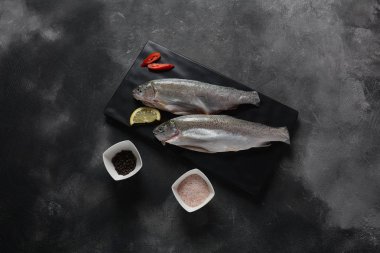 Tuz, biber, koyu arka planda limon ile taze alabalık 