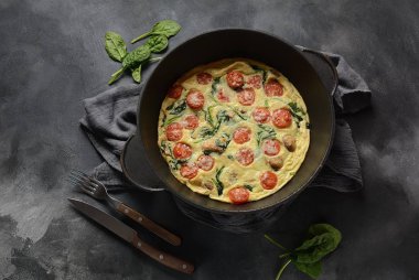 Frittata yumurta, mantar, kiraz domates ve ıspanak yapılan bir tavada servis edilir. İtalyan mutfağı.