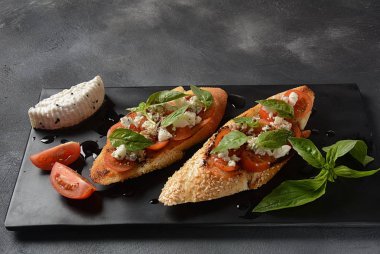 Kiraz domates, mozzarella ve fesleğen ile Caprese bruschetta tost. İtalyan antipasti atıştırmalıkları ile mezeler. 