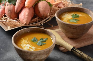 Tatlı patates ve havuç çorbası ahşap kase de ekşi krema ile servis edilir. Portakallı sebze çorbası konsepti. Vegan gıda