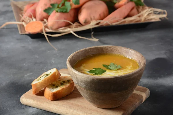 Tatlı patates ve havuç çorbası ahşap kase de ekşi krema ile servis edilir. Portakallı sebze çorbası konsepti. Vegan gıda