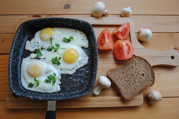 在平底锅中煎鸡蛋 在木制背景上享用早餐 包括西红柿和面包 美味健康的自制早餐理念 — 图库照片
