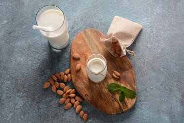 Arka planda badem ile cam şişelerde Badem sütü. Vegan günlük kavramı. Sağlıklı yiyecek ve içecekler 