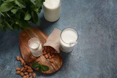 Arka planda badem ile cam şişelerde Badem sütü. Vegan günlük kavramı. Sağlıklı yiyecek ve içecekler 