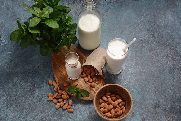 Almond milk in glass bottles with almonds on background. Vegan diary concept. Healthy food and drinks