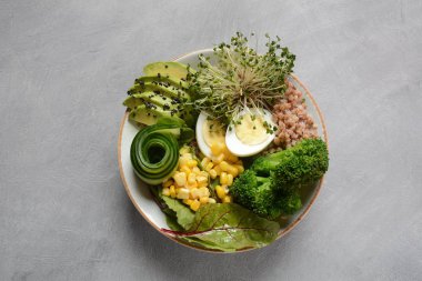 Haşlanmış yumurta, avokado, mısır, arugula pancar yaprakları, taze salatalık, karabuğday, brokoli filizi ile Yeşil vejetaryen Buda kase öğle yemeği. Sağlıklı vegan gıda konsepti 