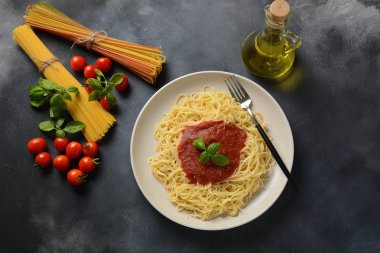 Koyu masa üzerinde plaka üzerinde domates sosu ve fesleğen ile klasik Italyan spagetti makarna 