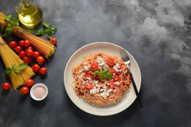 Klasik Italyan spagetti makarna ile domates sosu, mozzarella, kiraz domates ve fesleğen plaka üzerinde koyu masa