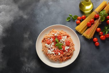Klasik Italyan spagetti makarna ile domates sosu, mozzarella, kiraz domates ve fesleğen plaka üzerinde koyu masa