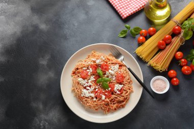 Klasik Italyan spagetti makarna ile domates sosu, mozzarella, kiraz domates ve fesleğen plaka üzerinde koyu masa