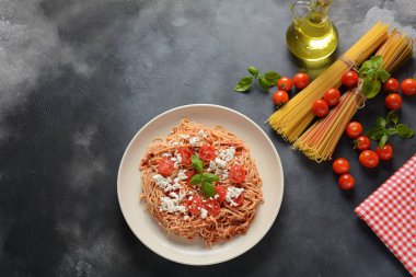 Klasik Italyan spagetti makarna ile domates sosu, mozzarella, kiraz domates ve fesleğen plaka üzerinde koyu masa