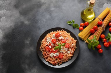 Klasik Italyan spagetti makarna ile domates sosu, mozzarella, kiraz domates ve fesleğen plaka üzerinde koyu masa