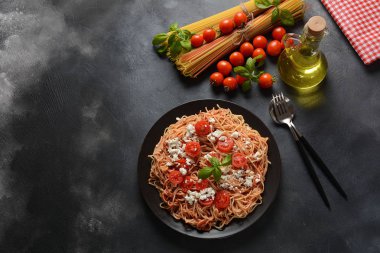 Klasik Italyan spagetti makarna ile domates sosu, mozzarella, kiraz domates ve fesleğen plaka üzerinde koyu masa