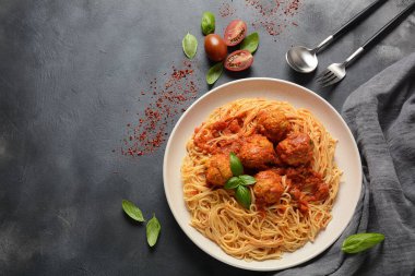 Koyu arka planda beyaz bir plaka üzerinde köfte ve domates sosu ile makarna spagetti