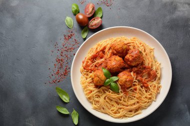 Koyu arka planda beyaz bir plaka üzerinde köfte ve domates sosu ile makarna spagetti