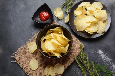 Gevrek ev Bowl ketçap, biberiye, otlar ve koyu arka plan üzerinde baharat ile servis patates cipsi yaptı. Abur cubur konsepti