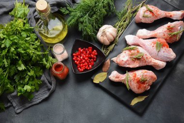 Tuz, otlar, sarımsak ve zeytinyağı ile barbekü ızgara için çiğ pişmemiş tavuk bacakları. Pişirme için malzemelerle et