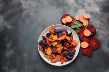 Fırında sebze cips- garnet tatlı patates, mor tatlı patates, havuç ve pancar. Glutensiz, sütsüz ve vegan. Sağlıklı gıda kavramı