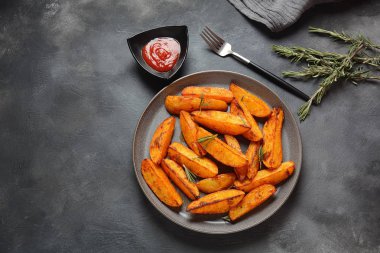 Fırında, baharatlı ve biberiyeli kızarmış patates dilimleri. 