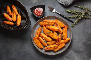 Fırında, baharatlı ve biberiyeli kızarmış patates dilimleri. 