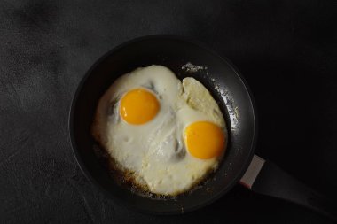 Dökme demir tavada iki sahanda yumurta bir masada sağlıklı ve kolay bir kahvaltı. Kızartma tavasında taze ev yapımı yemek. Geleneksel kahvaltı yemekleri. Uluslararası mutfak yemekleri. Üst görünüm.
