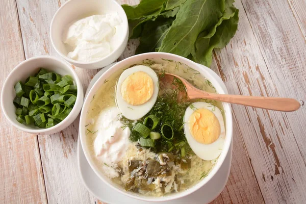 Green sorrel and spinach soup with boiled egg, spring onion and sour cream on white wooden rustic table. Diet or healthy food concept — Stock Image Green Sorrel Spinach Soup Boiled Egg Spring Onion Sour Cream Royalty Free Stock Photos