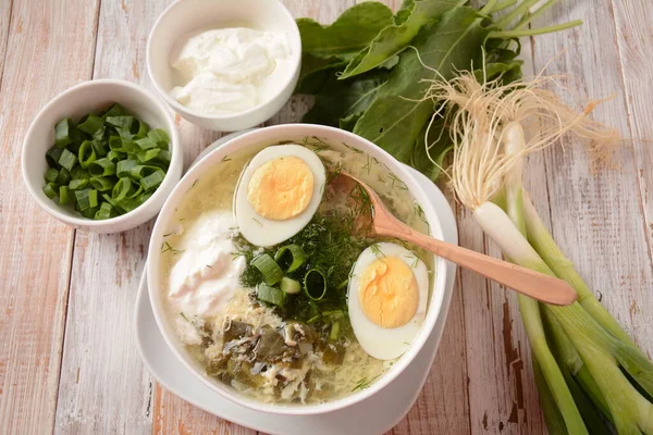 Green sorrel and spinach soup with boiled egg, spring onion and sour cream on white wooden rustic table. Diet or healthy food concept — Stock Image Green Sorrel Spinach Soup Boiled Egg Spring Onion Sour Cream Royalty Free Stock Photos